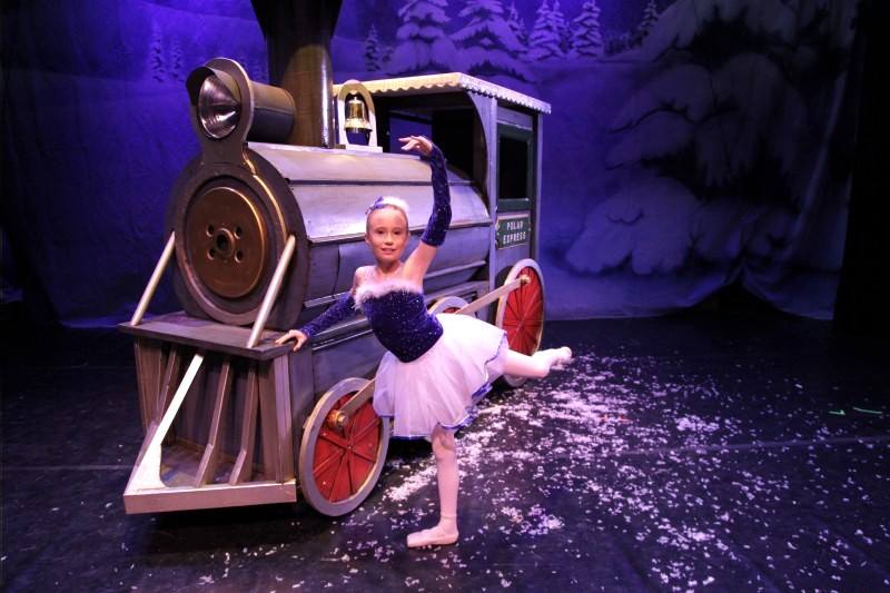 small girl posed in a ballet costume with a train set piece