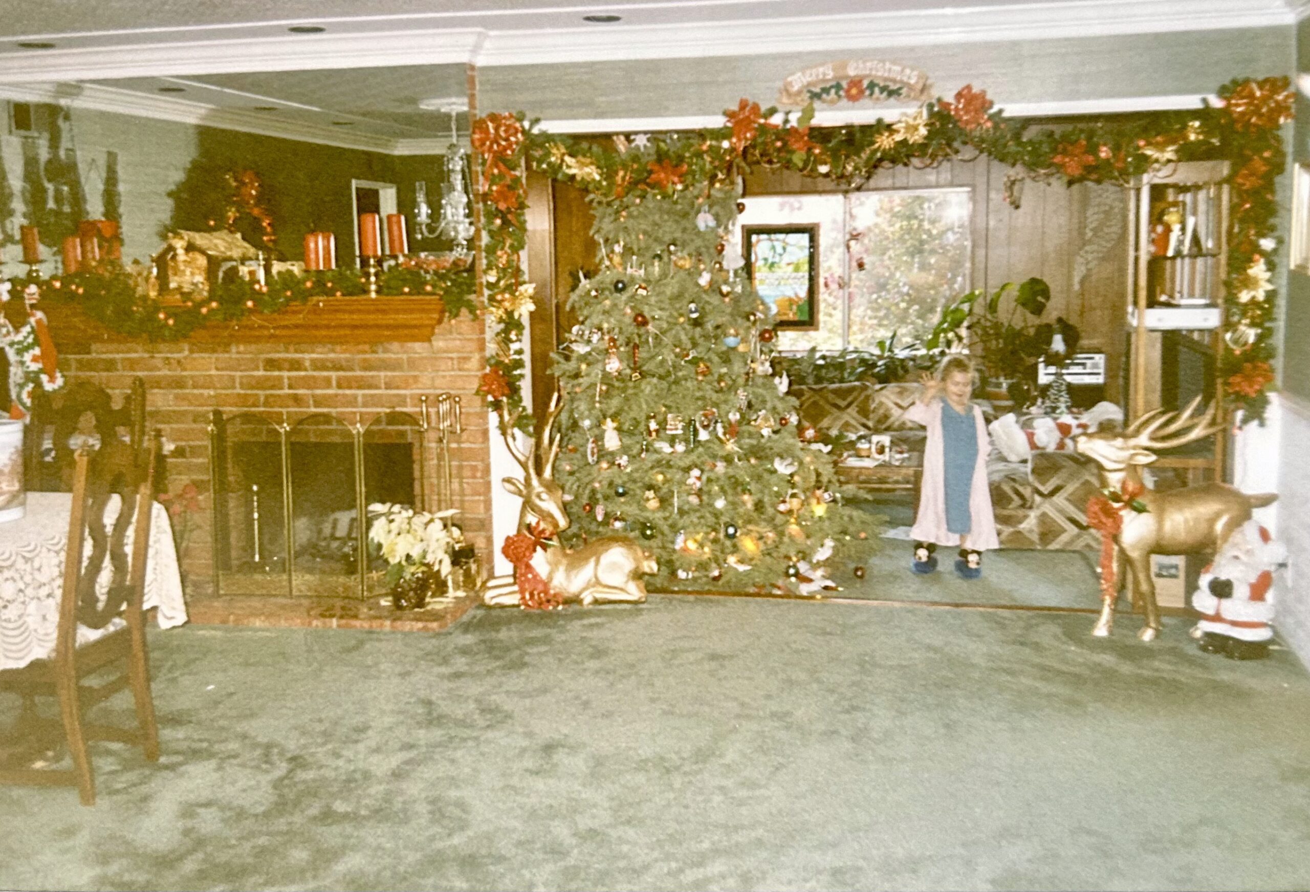 small girl next to christmas tree in decorated living room.
